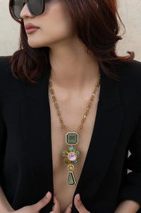 Woman wearing a gold necklace with gemstones against a neutral background