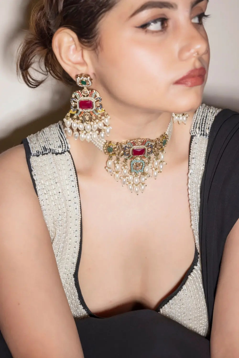 Close-up of a person wearing elaborate jewelry with a neutral background